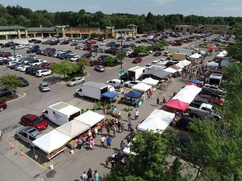 Parking lot with canopy tents, people and vehicles
