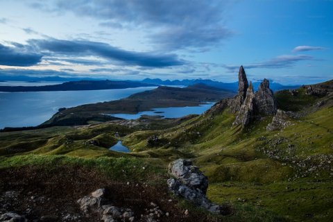 A large rock formation surrounded by water and grass