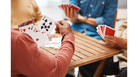 peoples hands holding playing cards