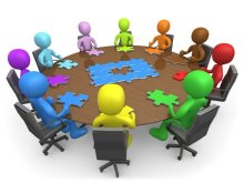 Group of individuals sitting around a circle table with a puzzle piece in front of them to represent each individual