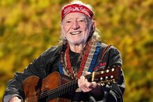a portrait of Willie Nelson holding his guitar